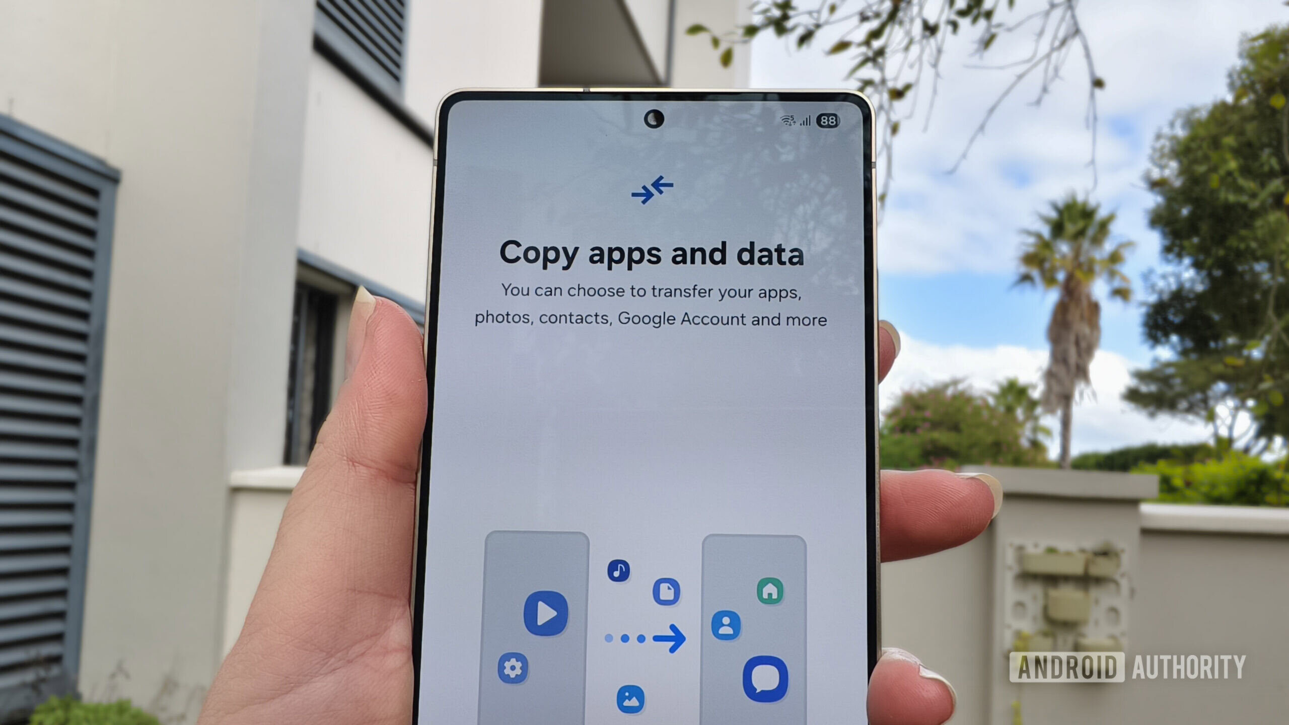 a smartphone held in a hand with a prompt to copy apps and data