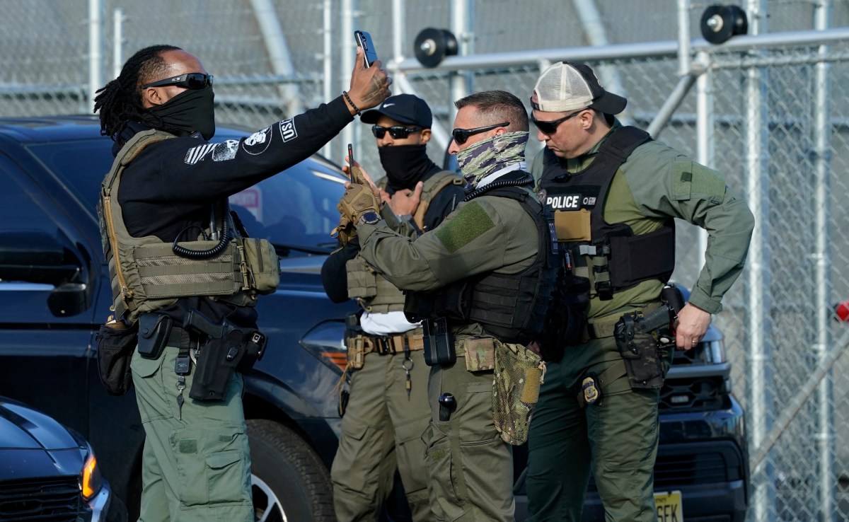 Immigration and Customs Enforcement (ICE) agents use their phones near protestors at a demonstration in Elizabeth, New Jersey May 7, 2025, outside Delaney Hall, a newly converted immigrant detention centre.