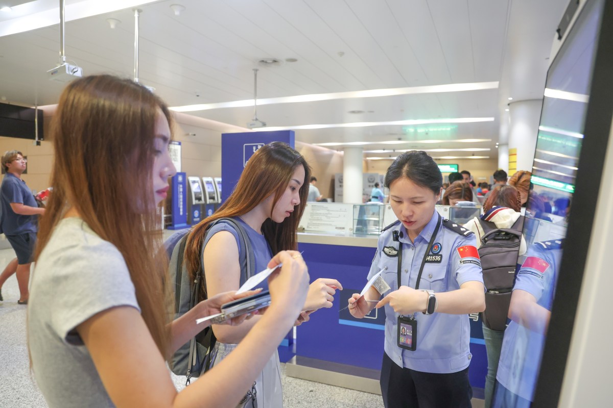 A border police officer answers questions from inbound passengers at Chongqing Jiangbei International Airport in southwest China's Chongqing, July 8, 2025.