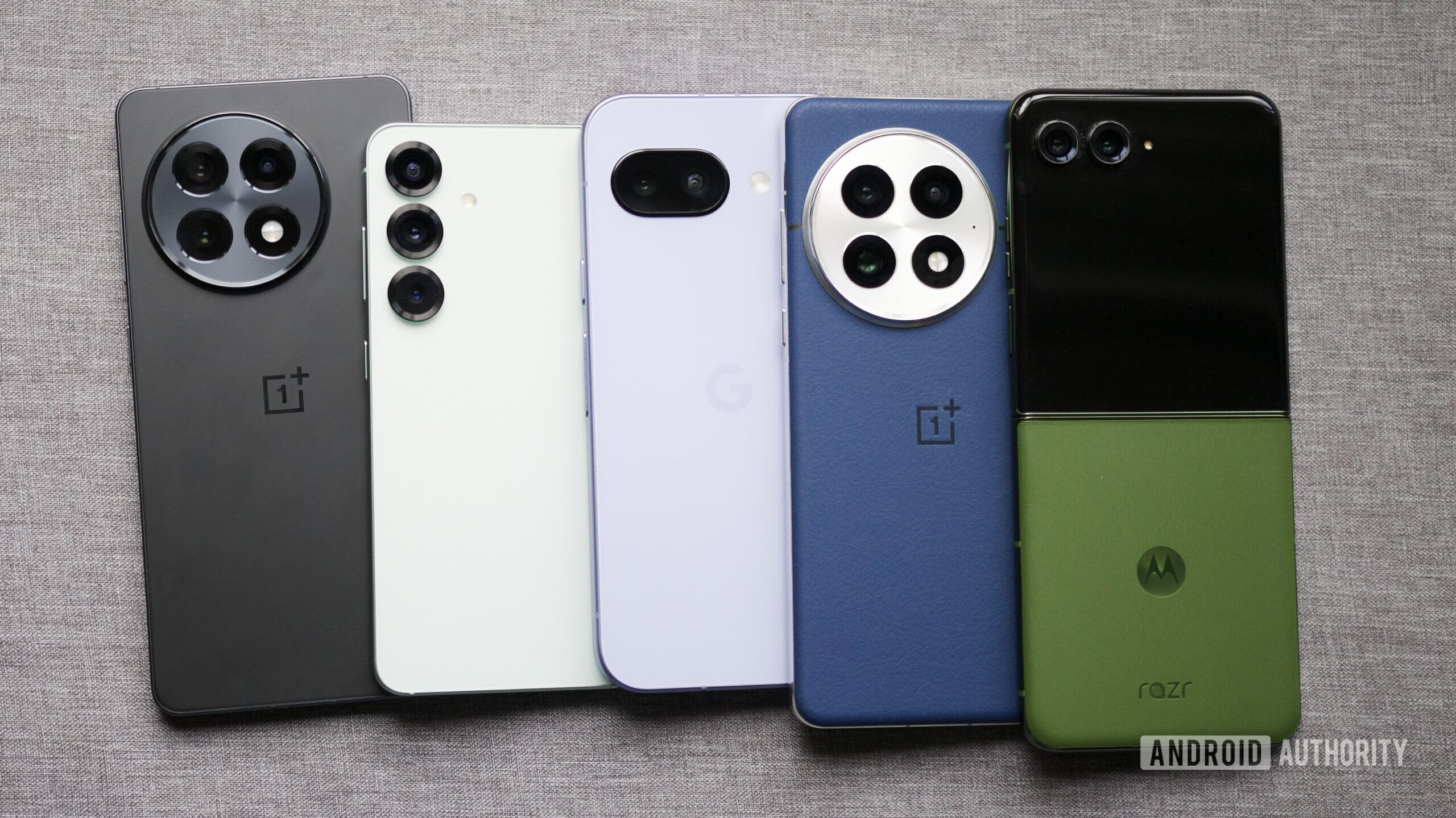 The OnePlus 13R, Galaxy S25, Pixel 9a, OnePlus 13, and Motorola Razr Plus (2024) are laying next to each other.